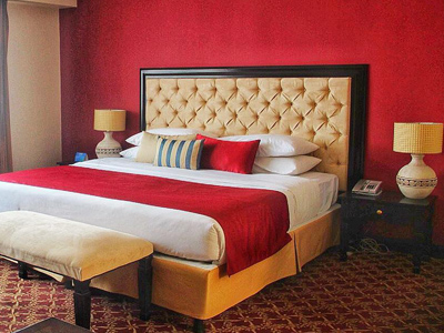 Picture of a beautiful Jr. Suite at the Costa Rica Medical Center Inn, San Jose, Costa Rica.  The picture shows cherry red and white bed sheets against a cherry red and white colored wall.