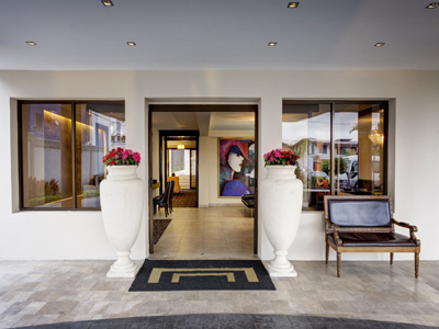 18-	Picture of the entrance of the Costa Rica Medical Center Inn, San Jose, Costa Rica.  The picture shows white exterior walls and a designer interior.